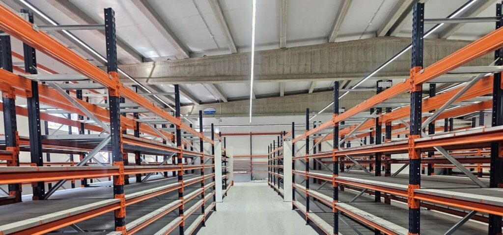 Pasillos entre estanterías metálicas iluminados mediante líneas continuas LED suspendidas en nave industrial de Béjar, Salamanca