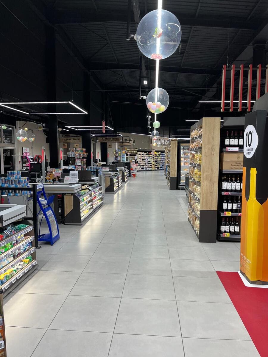 Luminarias lineales suspendidas de bajo deslumbramiento en pasillo de alimentos frescos.
