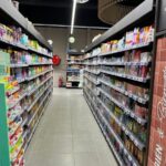 Iluminación ambiental difusa en la zona de cajas y entrada principal del supermercado.