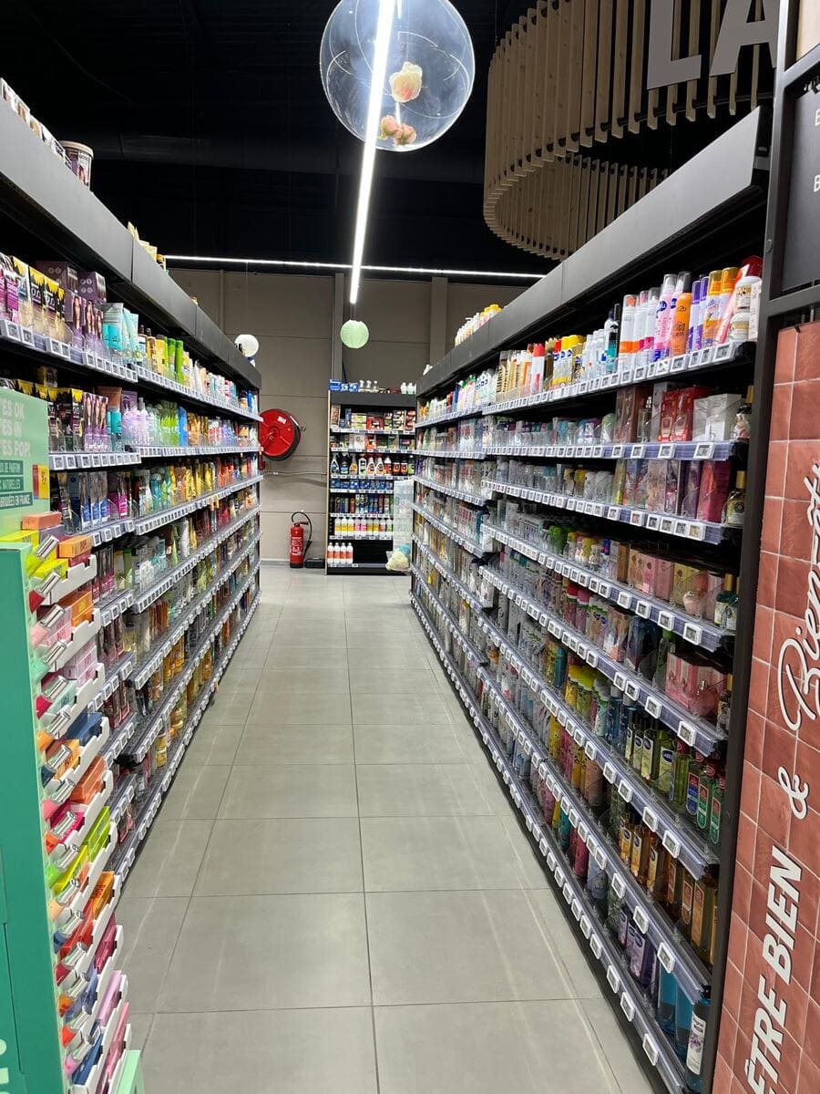 Iluminación ambiental difusa en la zona de cajas y entrada principal del supermercado.